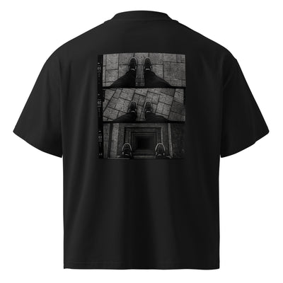 Dreiteilige Perspektive von oben auf die eigenen Füße auf Pflastersteinen, die zuletzt am Rand eines tiefen quadratischen Schachts stehen – FLOOR DROP Oversized T-Shirt von NiZED, Schwarz, Rückenansicht
