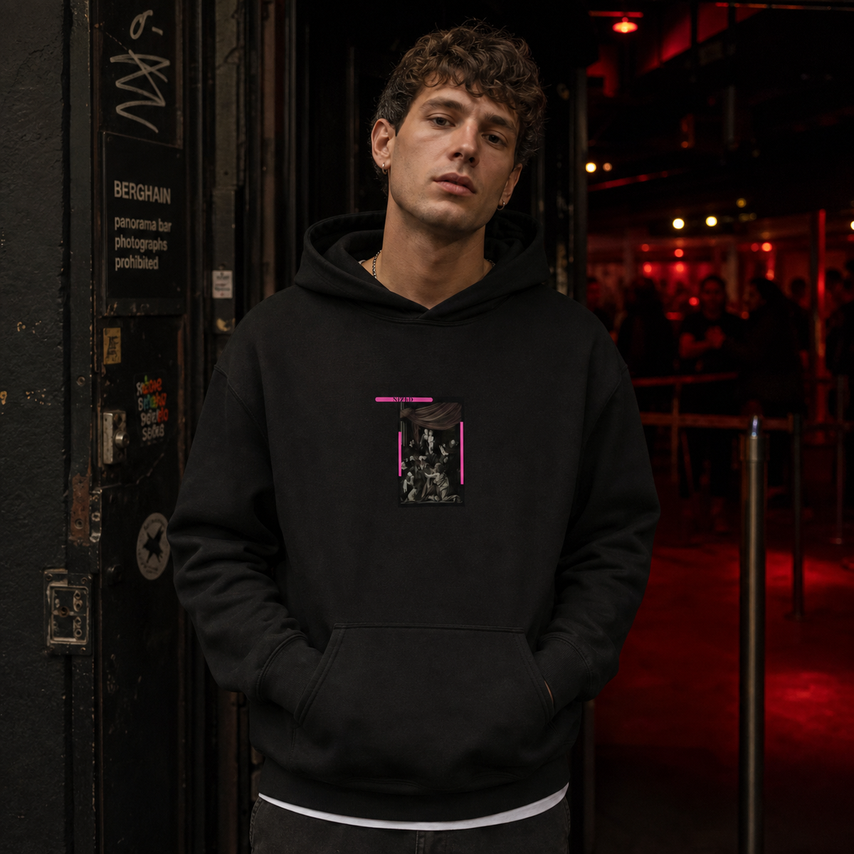 Männliches Model trägt den schwarzen Divine Spirit Hoodie von NiZED mit klassischem Frontmotiv vor Berliner Clubkulisse – KI-generierte Darstellung