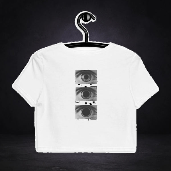 All Eyez On Me Crop Top von NiZED, Vorderansicht mit Designprint vor dunklem Betonhintergrund