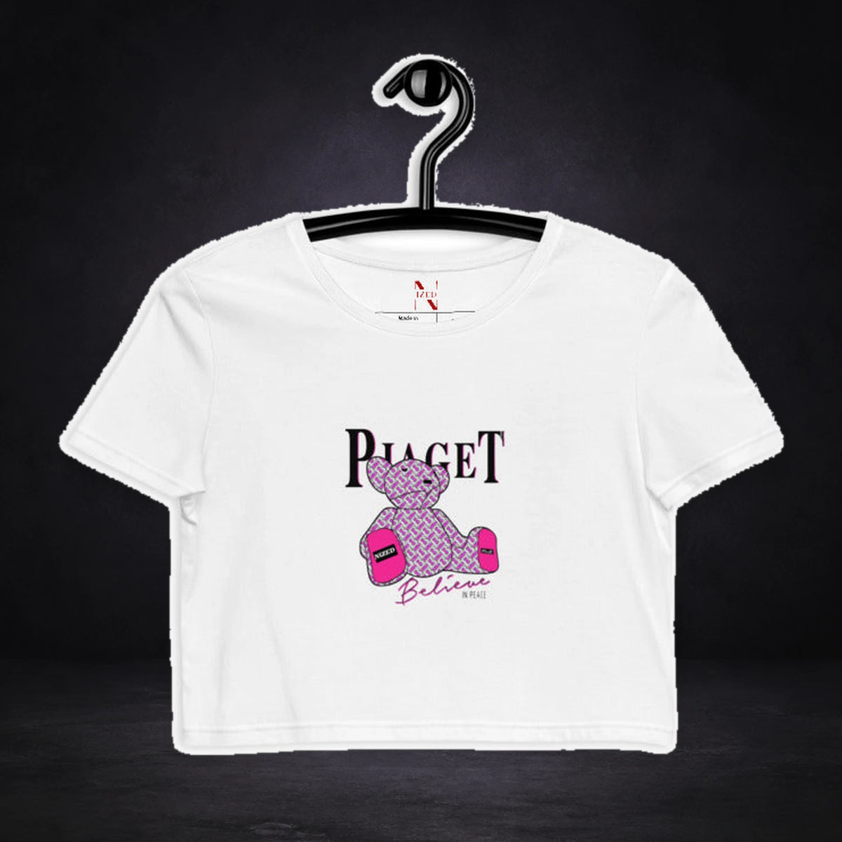 Belive Peace Crop Top von NiZED, Vorderansicht mit Designprint vor dunklem Betonhintergrund