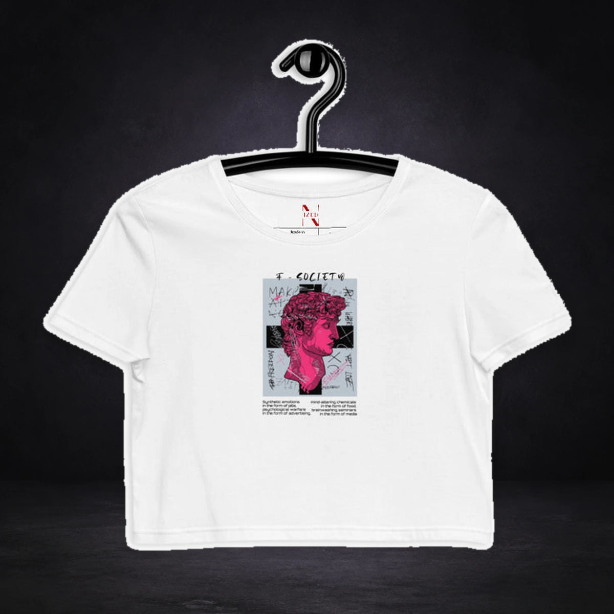 Society Crop Top von NiZED, Vorderansicht mit Designprint vor dunklem Betonhintergrund