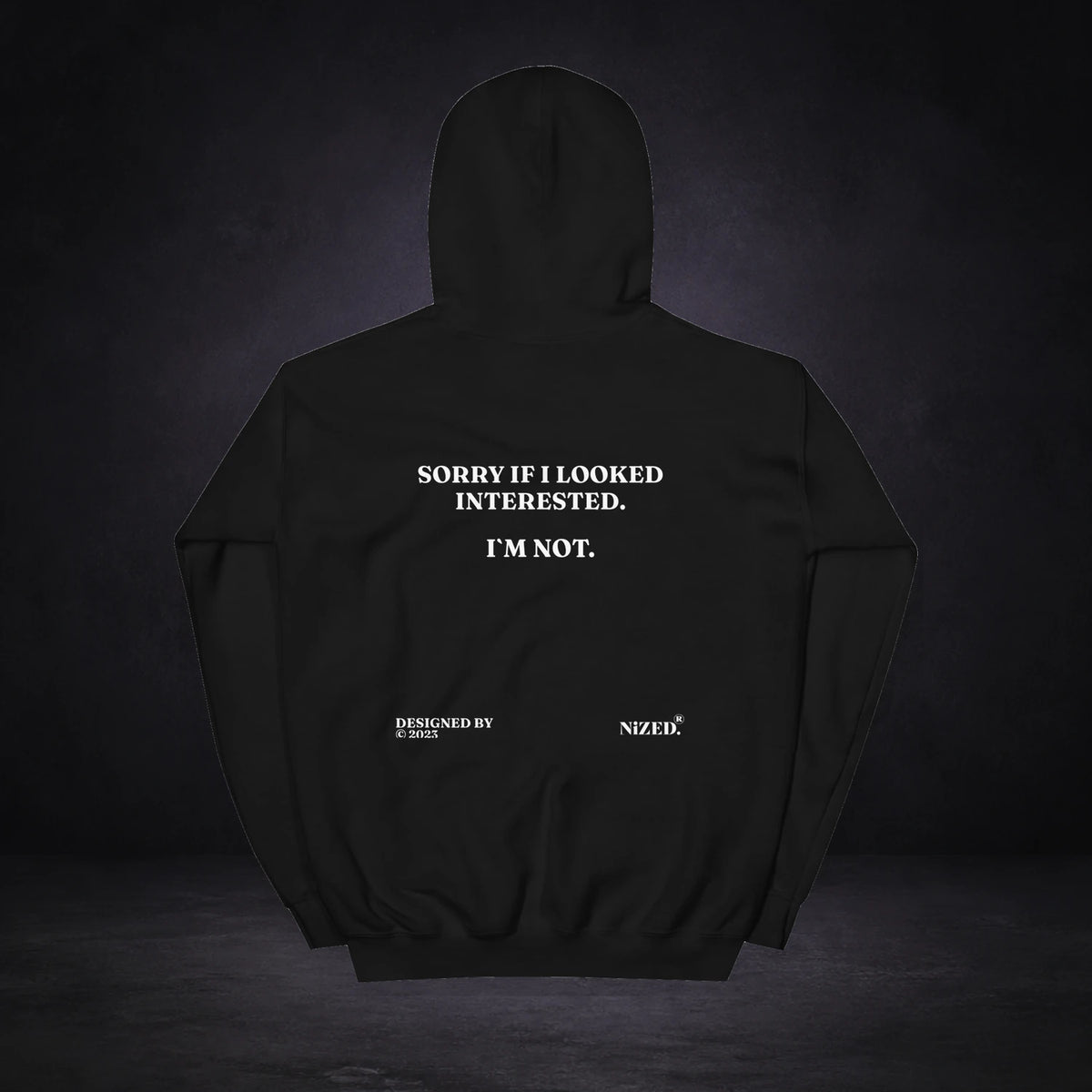 Sorry If I Looked Interessted But I´m Not Hoodie von NiZED, Rückansicht mit Designprint vor dunklem Betonhintergrund