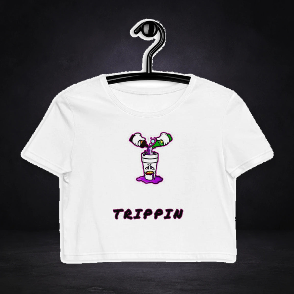 Trippin Tonic Crop Top von NiZED, Vorderansicht mit Designprint vor dunklem Betonhintergrund