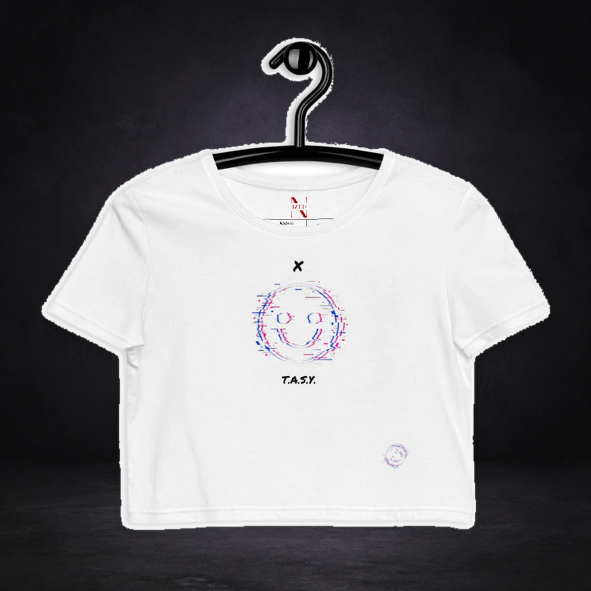 Xtasy Crop Top von NiZED, Vorderansicht mit Designprint vor dunklem Betonhintergrund