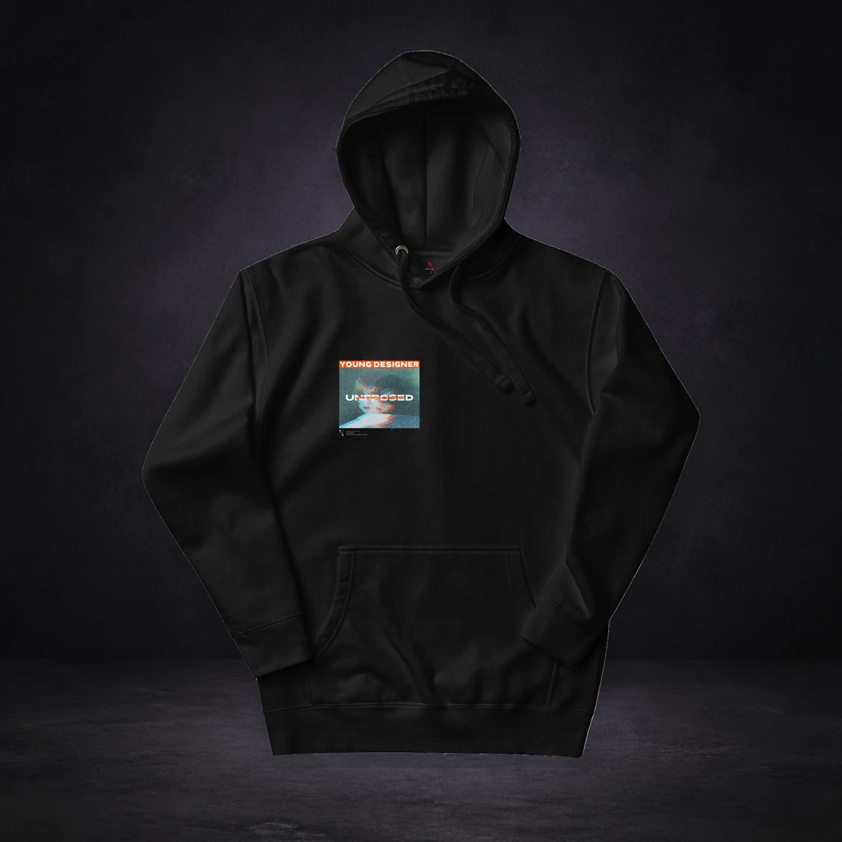 Young Designer Hoodie von NiZED, Vorderansicht mit Designprint vor dunklem Betonhintergrund