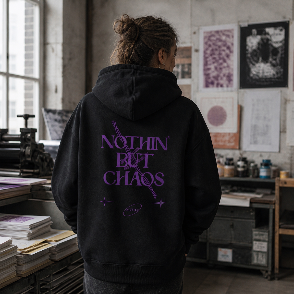 Nothing But Chaos Hoodie am weiblichen Model mit großem Backprint in einem Berliner Grafikstudio – KI-generierte Darstellung